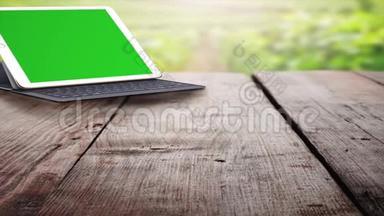 绿色屏幕平板电脑。 户外木桌上的平板电脑和键盘。 更换图像的绿色屏幕画面